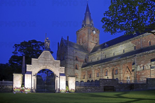 Illuminated historic church with clock tower and memorial in the evening, St Magnus Cathedral, Kirkwall, Orkney Islands, Orkneys, Scotland, United Kingdom