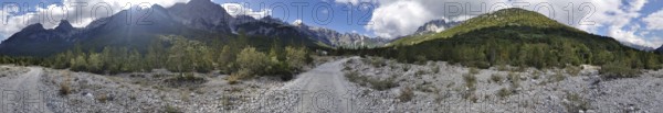 Panorama, dirt road through a wooded mountain landscape under a cloudy sky, Albanian Alps National Park