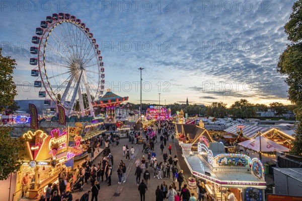 Ferris wheel, chain carousel, food stalls and visitors at the Cannstatter Volksfest, Cannstatter Wasen, Stuttgart, Baden-Württemberg, Germany