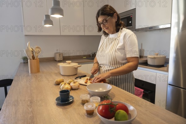 Woman preparing fresh vegetables on kitchen counter, chopping carrots and potatoes for homemade meal. Healthy eating, comfort food, and domestic lifestyle in a bright contemporary kitchen