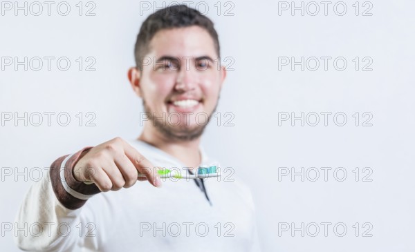 Portrait of happy young man showing toothbrush with toothpaste