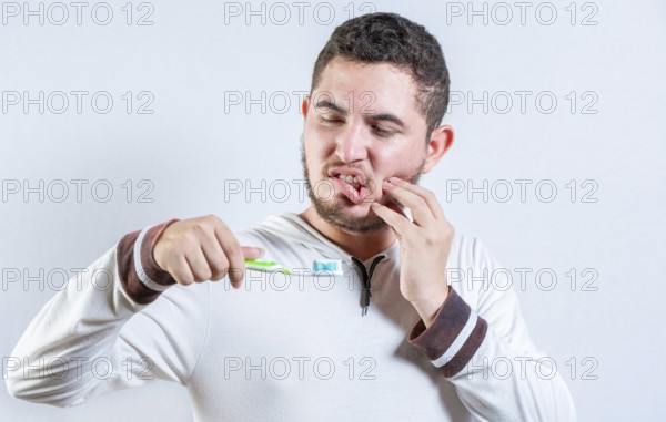 Guy with gum pain holding toothbrush. Suffering man with gingivitis holding toothbrush isolated
