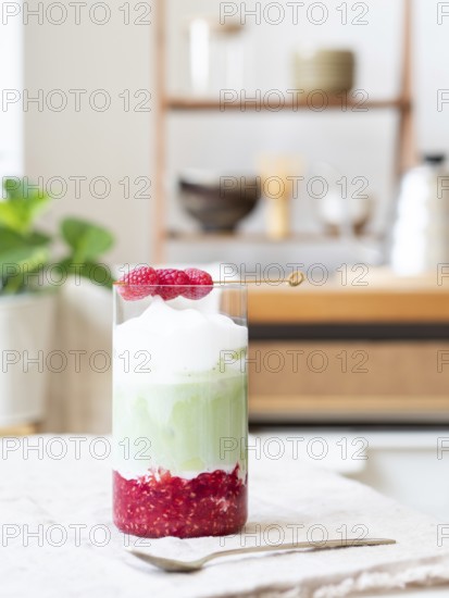 Refreshing layered iced matcha latte with raspberry puree and foamy topping