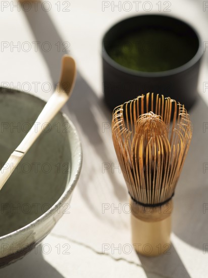 Preparing matcha green tea with traditional chasen, chawan, and chashaku on a bright table