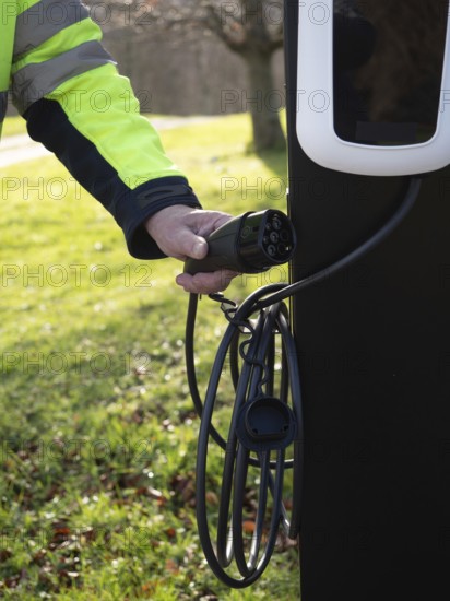 Worker holding an ev charging cable, representing sustainability and green energy