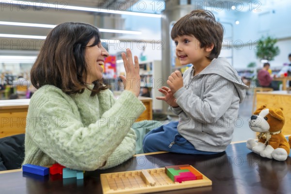 Mother and son smiling and high fiving while playing a colorful block strategy game at home, sharing a joyful learning moment and strengthening their bond through play