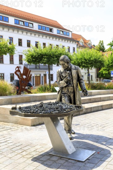Silver figure explorer traveling by Ekaterina Kovalenko on Castle Square with bronze model of the old town, stop on the Siberweg adventure trail through the old town of Freiberg, Saxony, Germany