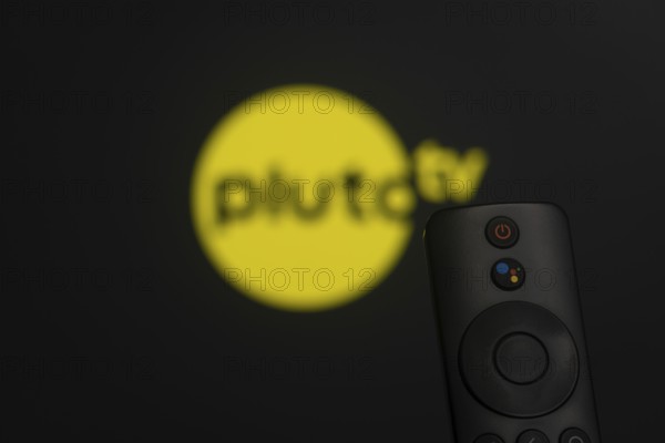 Dhaka, Bangladesh- 21 Jan 2026: Close-up of a smart TV remote control against a blurred pluto tv logo