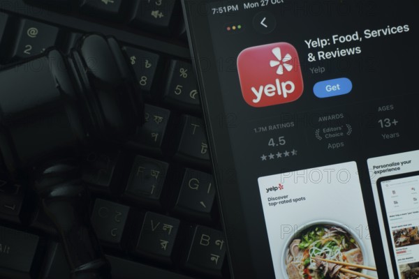 Dhaka, Bangladesh- 28 Oct 2025: An iPad displaying the Yelp app against a judge's gavel and dark keyboard background