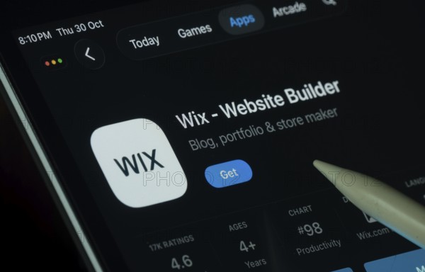 Dhaka, Bangladesh- 30 Oct 2025: Wix app displayed on a iPad screen in dark mode with a digital pen pointing at it