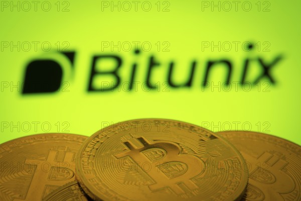 Dhaka, Bangladesh- 03 Sep 2025: Close-up of Bitcoin coins with the Bitunix logo visible on a screen in the background