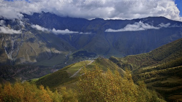 Panoramic view of an autumn mountain landscape under dramatic clouds, Stepantsminda, Caucasus, Georgia
