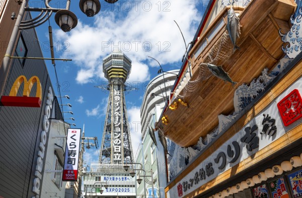 Lots of colorful signs in a pedestrian zone with shops and restaurants, behind Tsutenkaku Tower, Shinsekai, Osaka, Japan