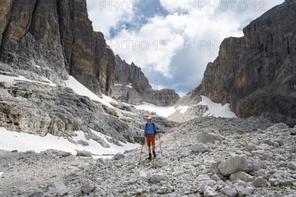 Hikers in a gap, Sentiero Brentari in front of rock faces, Brenta Mountains, Brenta-Adamello Natural Park, Trentino, Italy