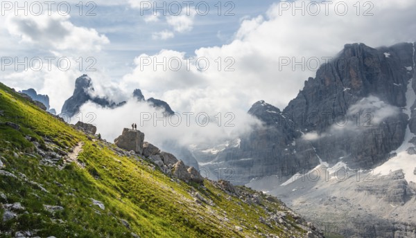 Alpine panorama, mountaineers on a large rock, fog and Torre Di Brentai and Cima Tosa, rocky mountain peaks and mountain landscape, Brenta Mountains, Parco Naturale Brenta-Adamello, Trentino, Italy