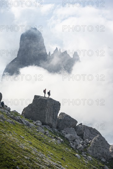 Alpine panorama, mountaineers on a large rock, fog and Torre Di Brentai and Cima Tosa, rocky mountain peaks and mountain landscape, Brenta Mountains, Parco Naturale Brenta-Adamello, Trentino, Italy