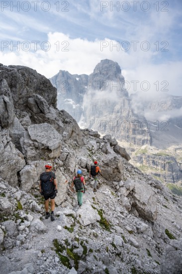 Three mountaineers on a hiking trail, rocky mountain landscape, Via Ferrata SOSAT via ferrata, Brenta Mountains, Trentino, Italy