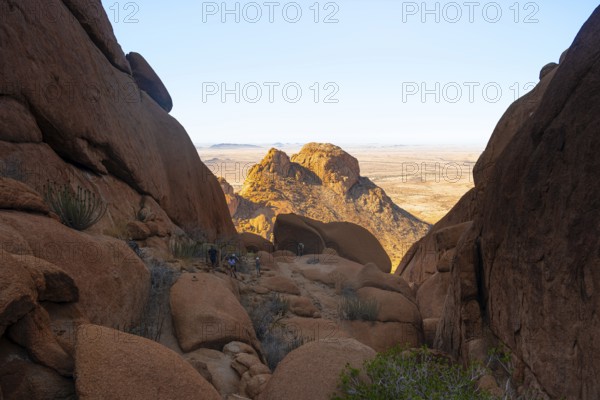 A crevice between rocks opens up a view of the dry desert landscape, Spitzkoppe, Namibia