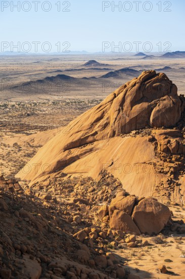Massive rocks rise in the endless expanse of desert against a clear sky, Spitzkoppe, Namibia