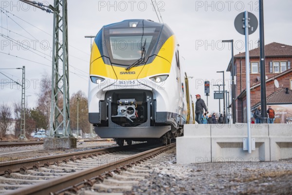 Modern locomotive on railroad tracks in front of buildings and power lines, opening of the Hermann Hesse Railway, Calw, Germany