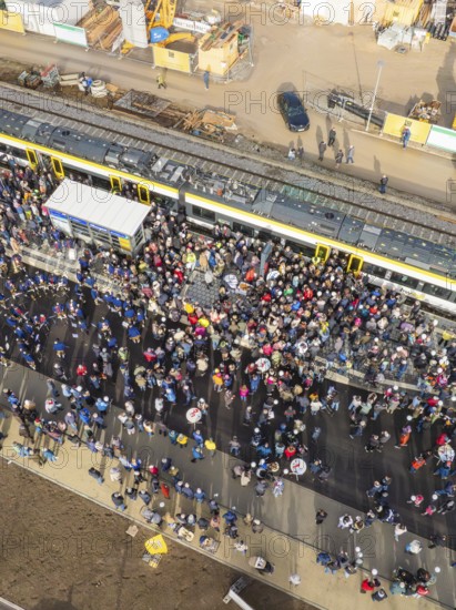 People gather around a parked train at a train station, aerial view, opening of the Hermann Hesse Railway, Calw, Germany