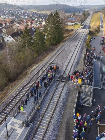 People standing along a railway line next to a small train station, village and countryside visible, opening of the Hermann Hesse Railway, Calw, Germany