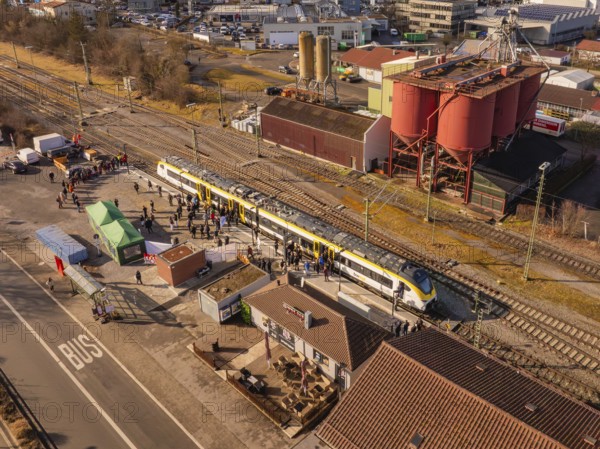 Industrial site with a passing train, surrounded by people and various buildings, opening of the Hermann Hesse Railway, Calw, Germany