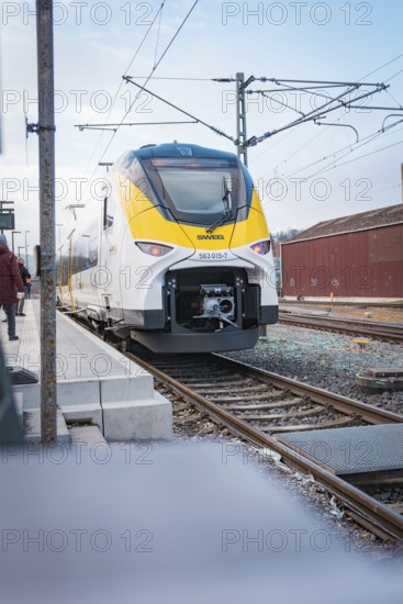A white-yellow train stands on a platform with people nearby, opening of the Hermann Hesse Railway, Calw, Germany