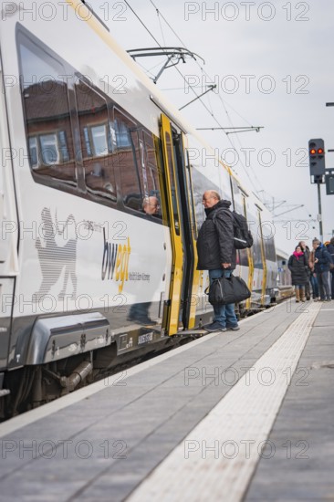 People board a train at a train station with a cool, cloudy atmosphere, opening of the Hermann Hesse Railway, Calw, Germany