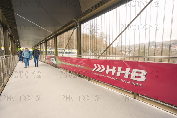 Pedestrian bridge with a large Hermann Hesse Railway banner and people crossing the bridge, opening of the Hermann Hesse Railway, Calw, Germany