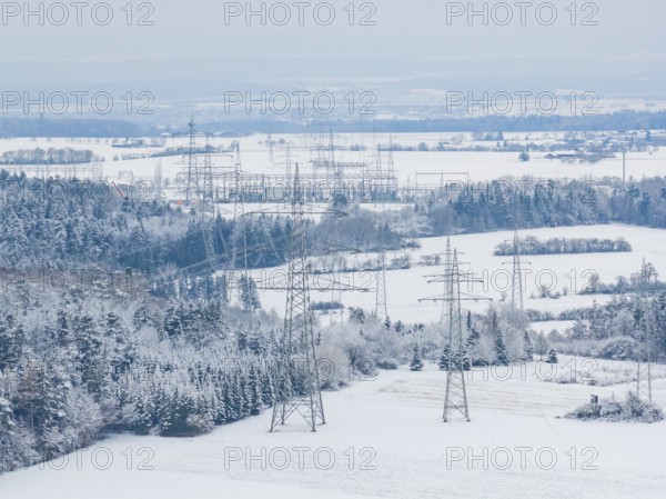 Snow-covered fields with electricity poles and a village in the background under a blue sky, substation, Jettingen, Germany