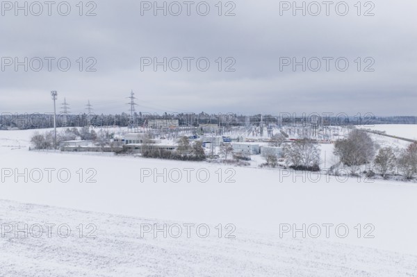 A wide snowy field with power lines and a substation in the distance, substation, Jettingen, Germany