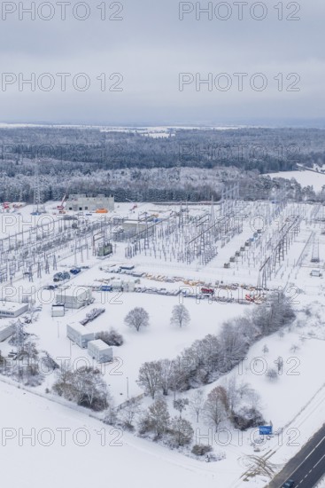 A snow-covered substation with power lines and surrounding trees in a winter landscape, substation, Jettingen, Germany