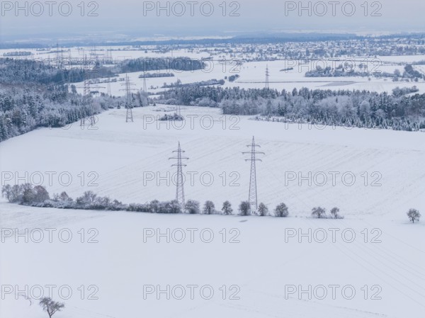 Wide snow-covered fields with power lines and small villages on the horizon in cold weather, substation, Jettingen, Germany