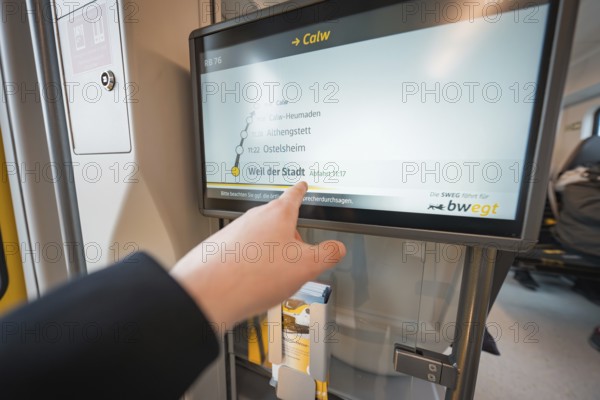 Display screen with timetable and hand showing departure time, battery electric train Siemens Micro Plus B, Hermann, Hesse, Bahn, Weil der Stadt, Böblingen district, Germany