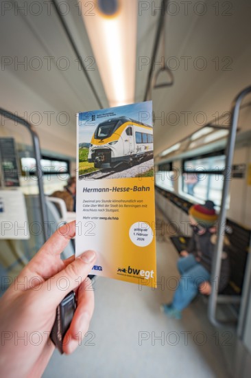 Hand holding brochure about the Hermann-Hesse railway inside the train, battery electric train Siemens Micro Plus B, Hermann, Hesse, Bahn, Weil der Stadt, Böblingen district, Germany