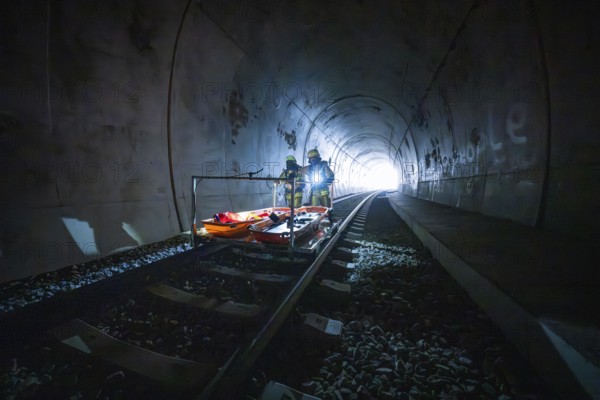Firefighters on an emergency vehicle in a dark tunnel at the end during daylight, fire drill at the Hermann-Hesse railway, Ostelsheim, Germany