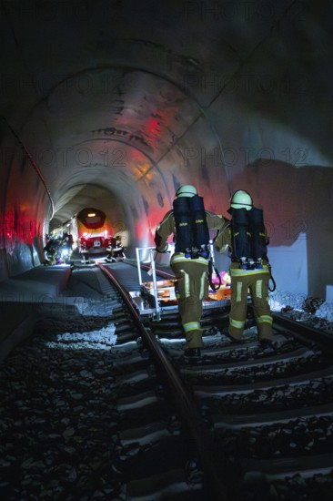 Firefighters walk on tracks through a dark tunnel with red light effects, fire drill on the Hermann Hesse Railway, Ostelsheim, Germany