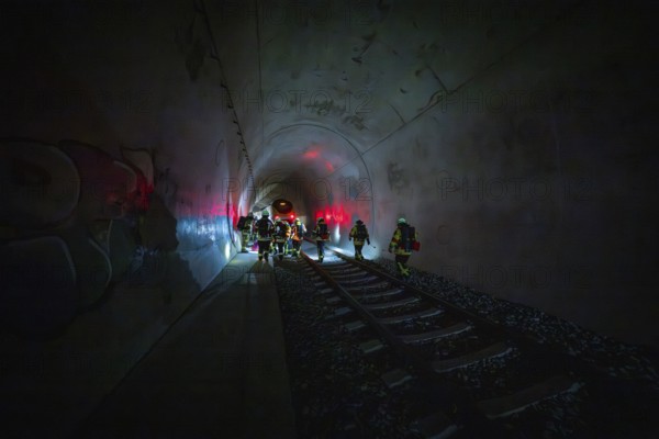 Groups of firefighters work in an illuminated tunnel with a dramatic atmosphere, fire drill on the Hermann Hesse Railway, Ostelsheim, Germany
