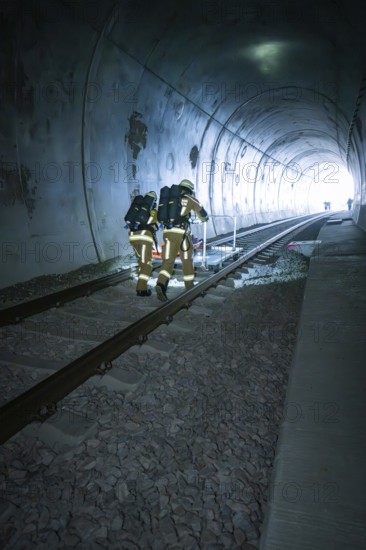 Firefighters in protective suits walk through a dark tunnel on tracks, fire drill on the Hermann Hesse Railway, Ostelsheim, Germany