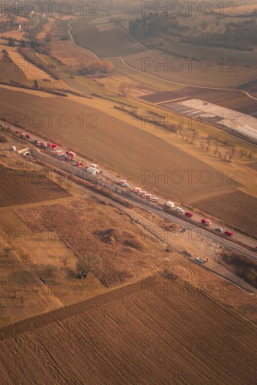 Emergency vehicle convoy on country road in vast, hilly landscape at dusk, fire drills on the Hermann-Hesse railway, Ostelsheim, Germany