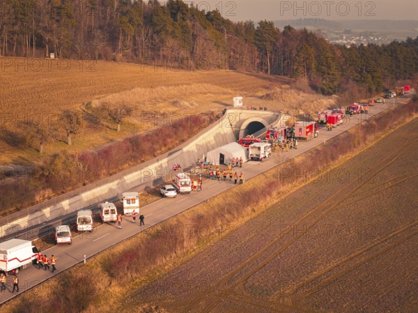 Emergency vehicles with firefighters near a tunnel next to fields and trees at dusk, fire drill on the Hermann Hesse Railway, Ostelsheim, Germany