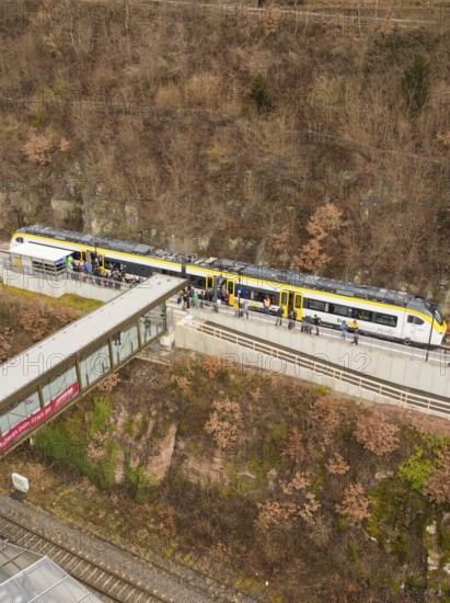 Train at a train station along a hill with bare trees and people waiting, opening of the Hermann Hesse Railway, Calw, Germany