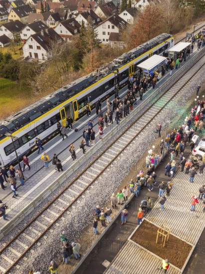 People stand close to the platform while a train stops in a village, opening of the Hermann Hesse Railway, Calw, Germany