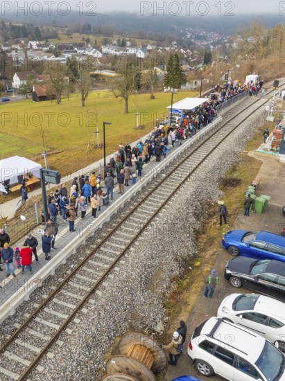 People stand next to parked cars at a railway station in rural surroundings, opening of the Hermann Hesse Railway, Calw, Germany