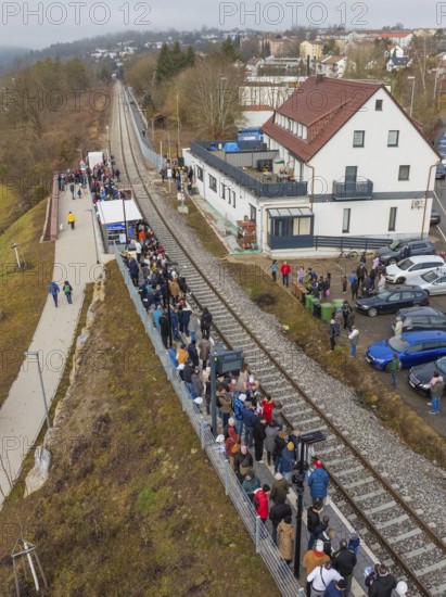 People wait for a train at a station along the tracks next to a road, opening of the Hermann Hesse Railway, Calw, Germany