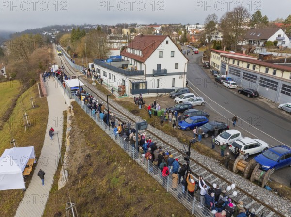 A crowd of people waits in a village along the railroad tracks next to a road, opening of the Hermann Hesse Railway, Calw, Germany