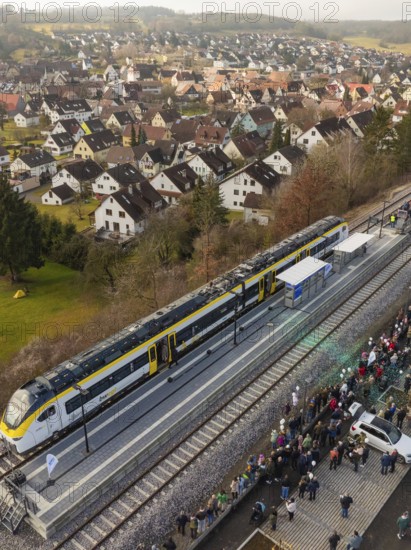 A train stops at the village station and many people are gathered. In the background, the village stretches over rolling hills, opening of the Hermann Hesse Railway, Calw, Germany
