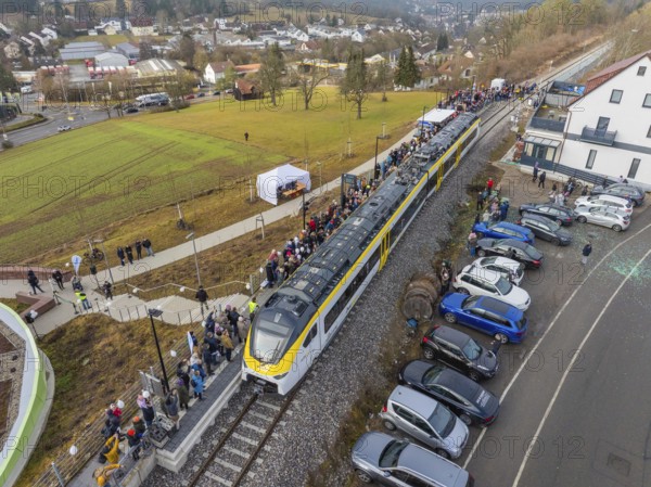 Train at a train station with people waiting and parked cars in a rural urban landscape, opening of the Hermann Hesse Railway, Calw, Germany