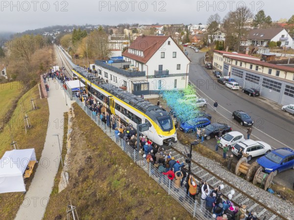 Aerial view of a train on a route with people and rain of confetti next to buildings during an event, opening of the Hermann Hesse Railway, Calw, Germany